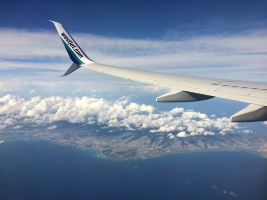 Plane wing with Oahu below, finding cheap flights
